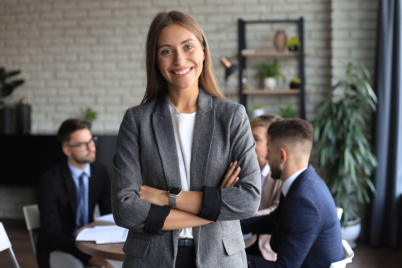 Business woman with her staff, people group in background at modern bright office indoors.