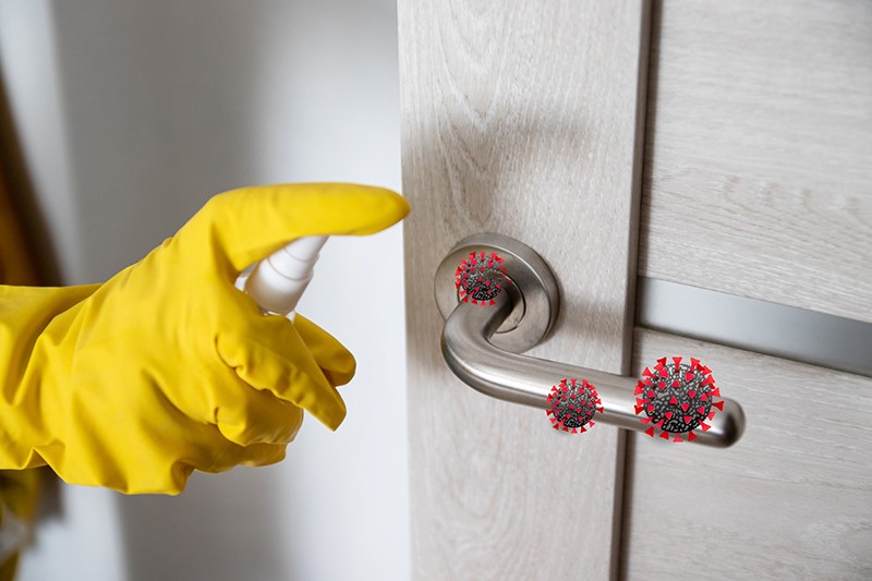 Hand with yellow glove using spray on door handles and hovering red germ renders